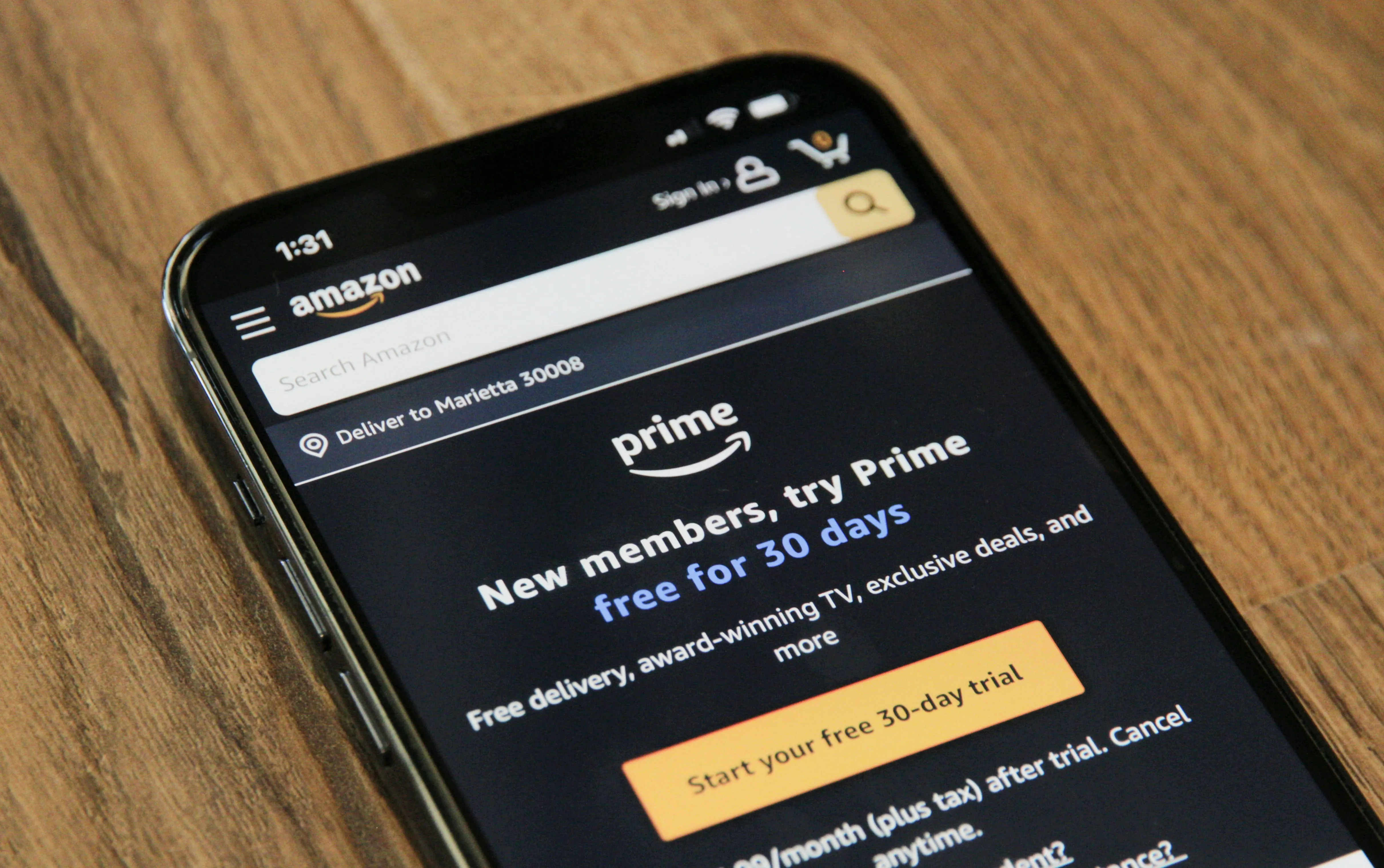 A smartphone resting on a wooden surface displaying the Amazon Prime free 30-day trial signup screen