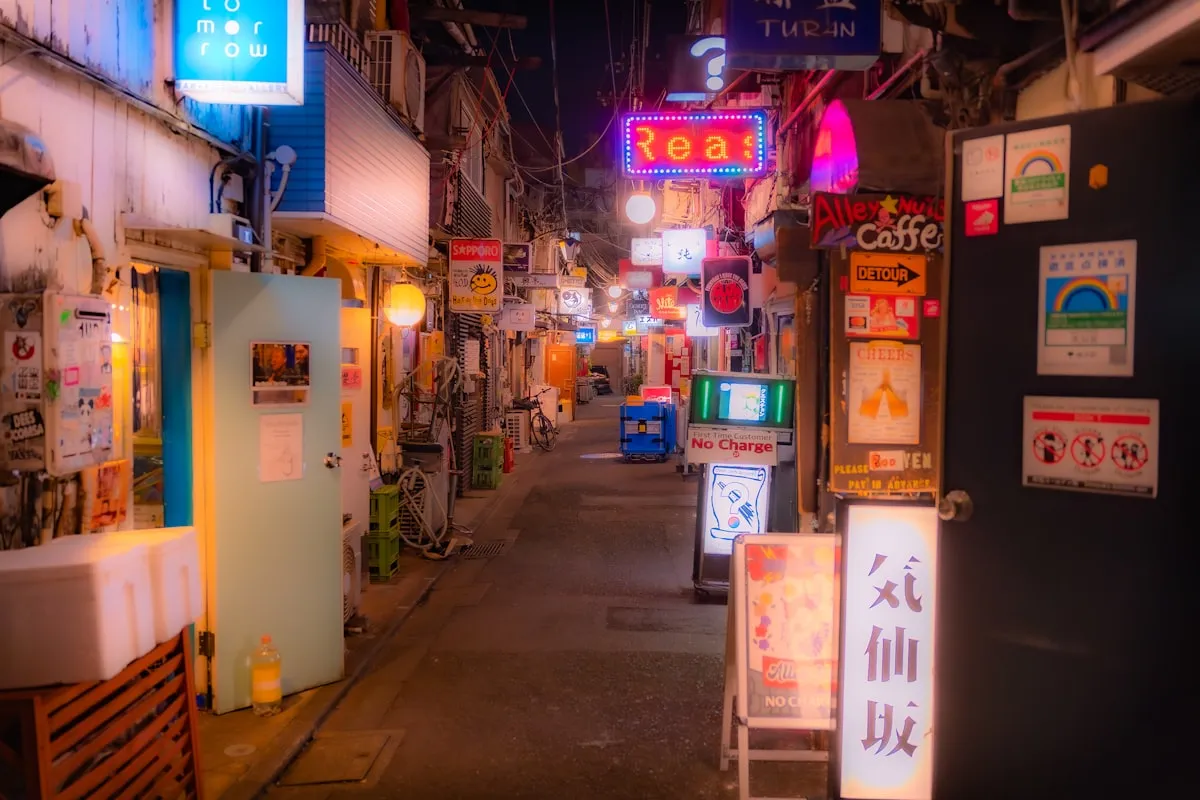 Narrow Tokyo alleyway at night packed with glowing Japanese signs for tiny bars and cafes, evoking anime-style cityscapes