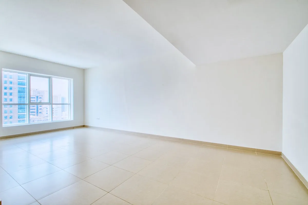 Empty white apartment living room with tile floors and a large window overlooking a city skyline, ready to be furnished
