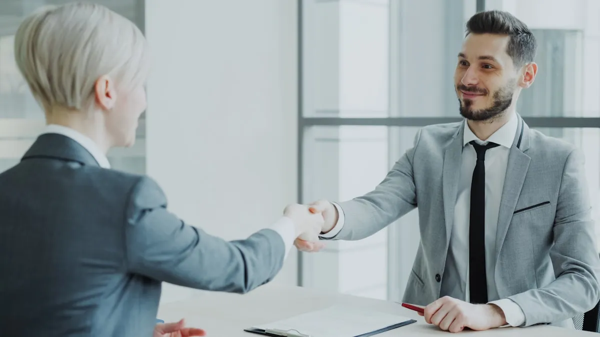 Two professionals in suits shaking hands across a desk after a job interview, with a contract document between them