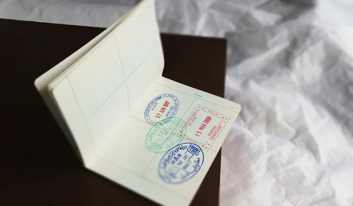 Open passport lying on a dark surface, showing a small handful of entry and exit stamps on otherwise blank pages