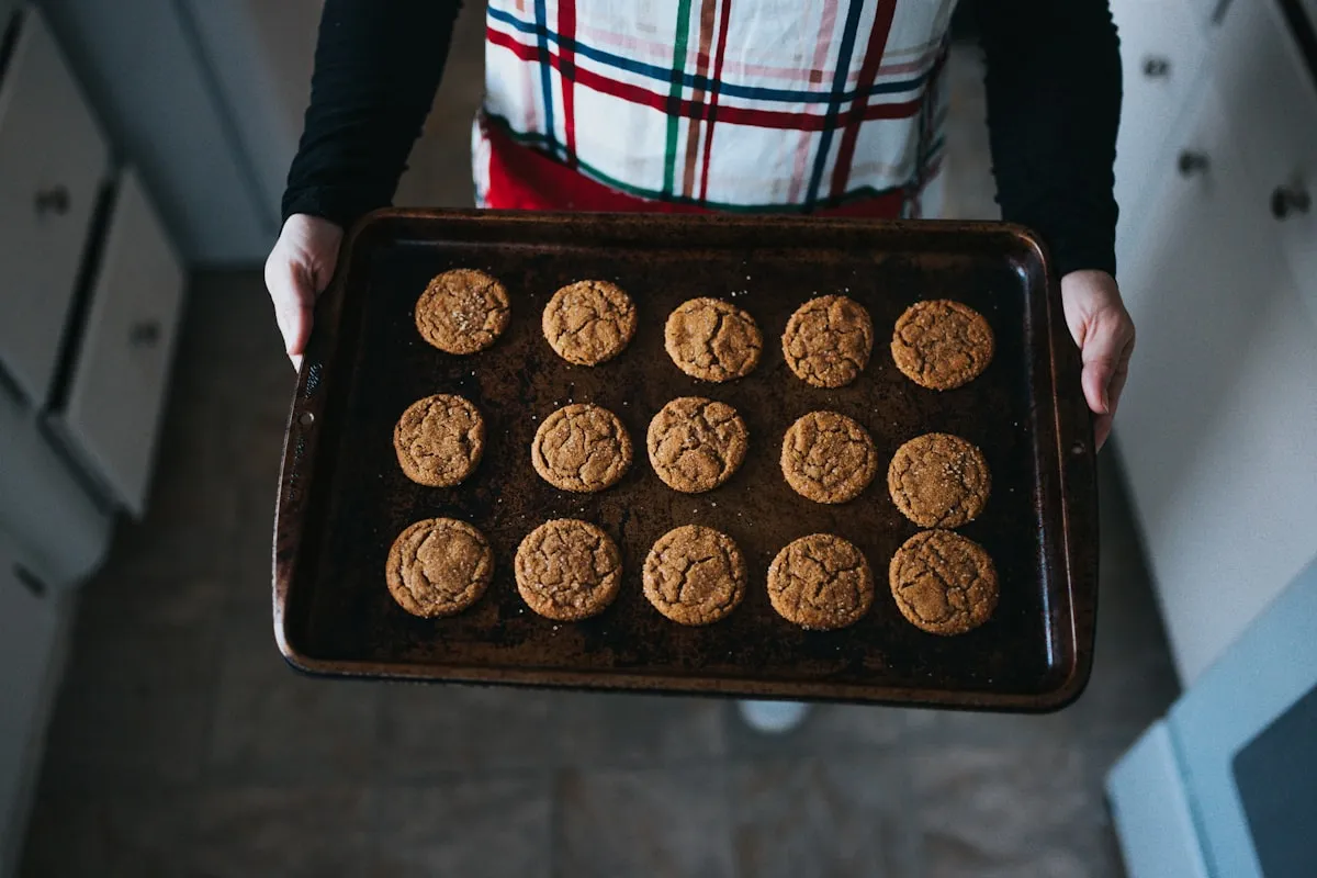 Home baker holding a tray of fresh-baked cookies in a warm summer kitchen