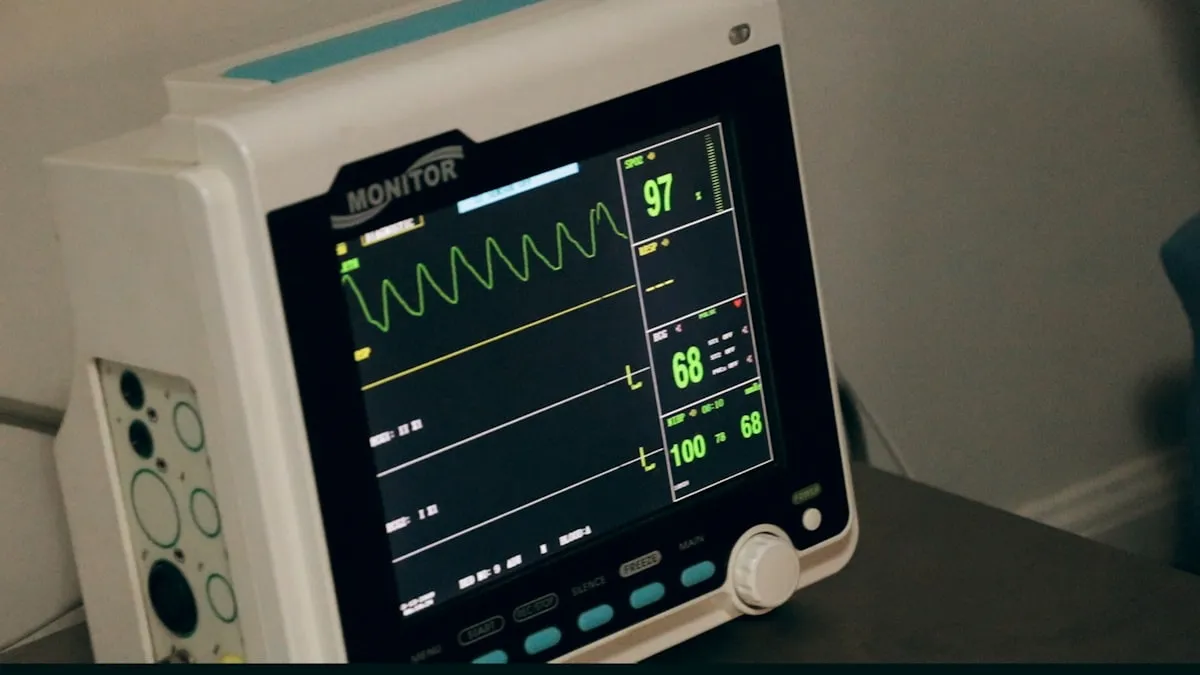 Bedside vital signs monitor showing a green pulse waveform, heart rate of 68 bpm, SpO2 of 97, and blood pressure 100/68